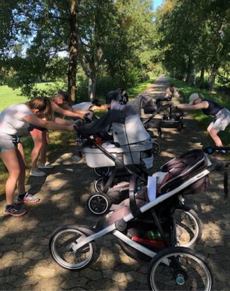 Eltern mit Kinderwagen bei einem Kurs im Freien